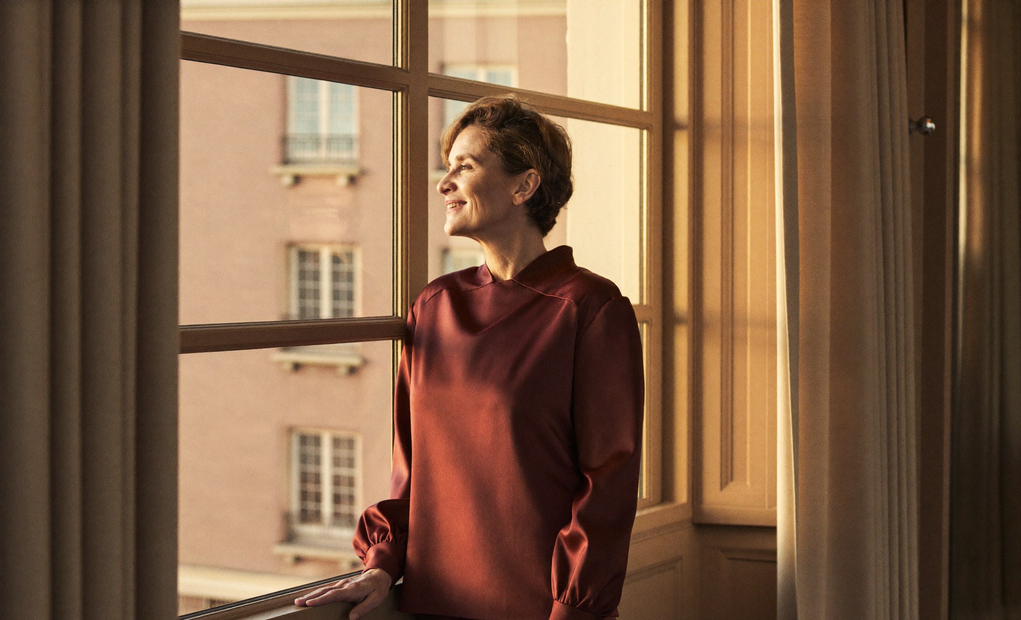 A poised, at-ease woman by a sunlit window, content with a long journey nearly complete