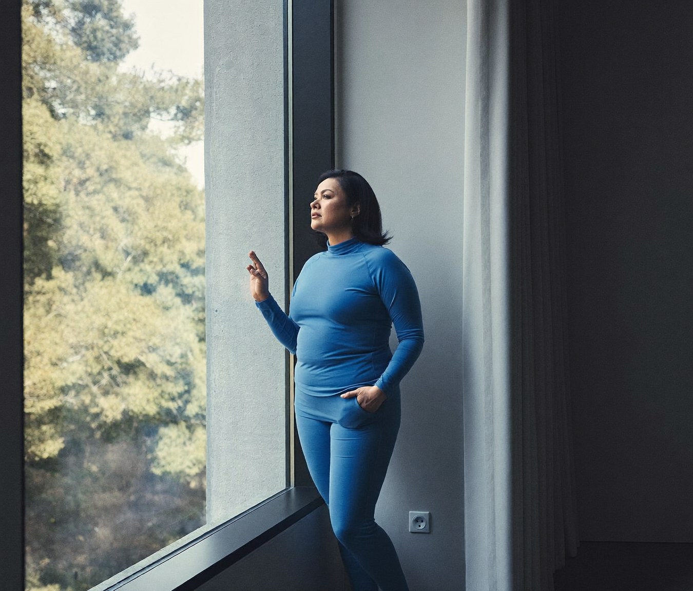 A poised, confident adult at ease by a window in a modern interior